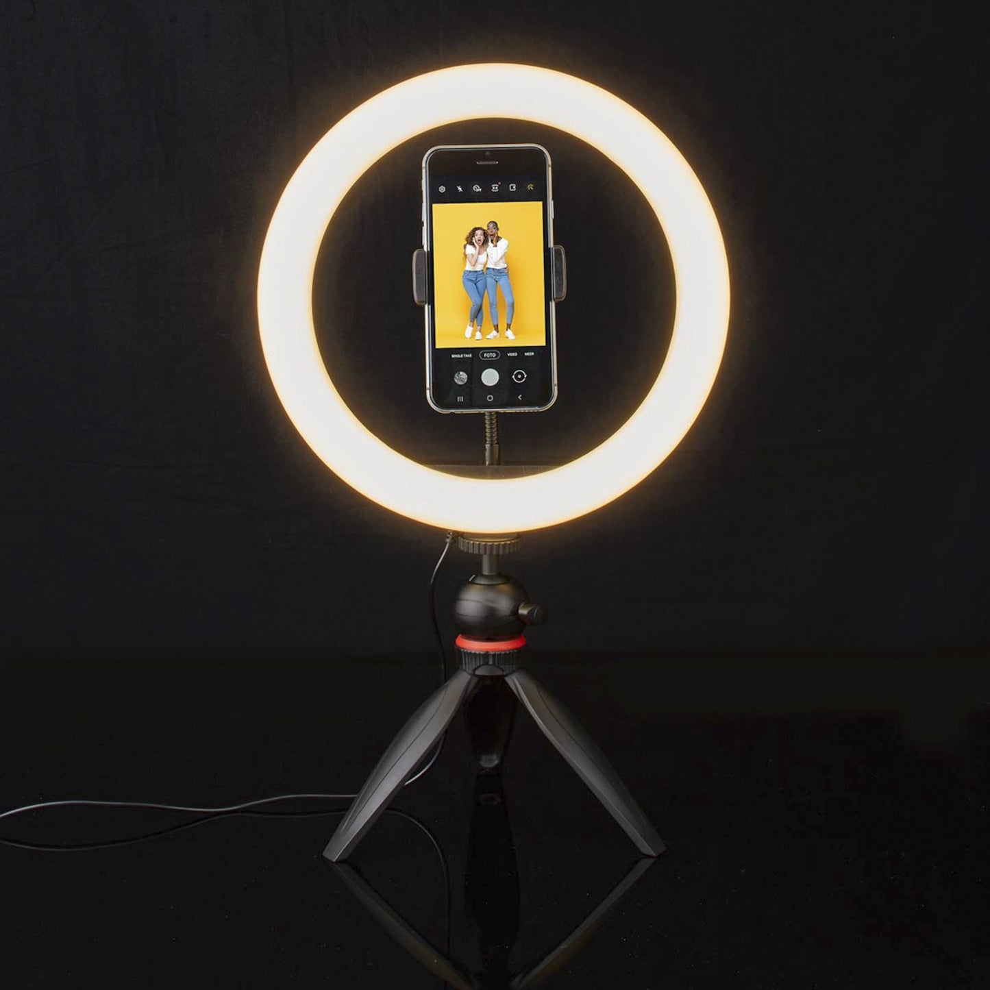 Nedis Ring Light 10" ringbelysning på stativ med smartphone monteret, til kvinder smiler på telefonskærmen.