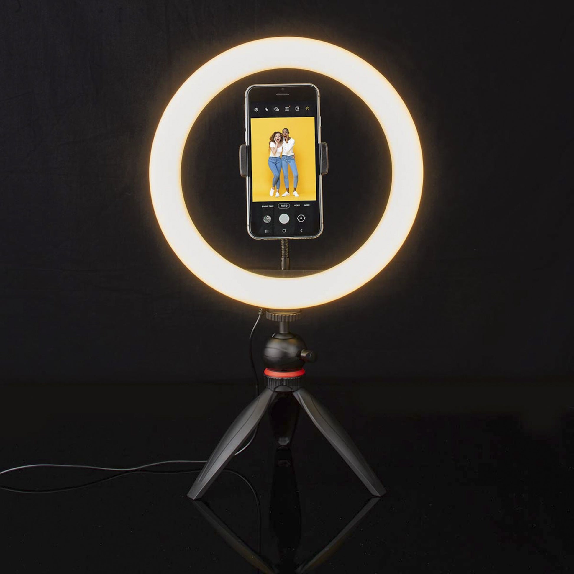 Nedis Ring Light 10" ringbelysning på stativ med smartphone monteret, til kvinder smiler på telefonskærmen.