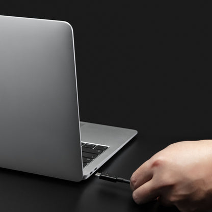 Plexgear Thunderbolt 4 USB-C kabel 80 cm sort holdes foran sølvfarvet laptop, synlig sort stikende, 40 Gb/s understøttet.