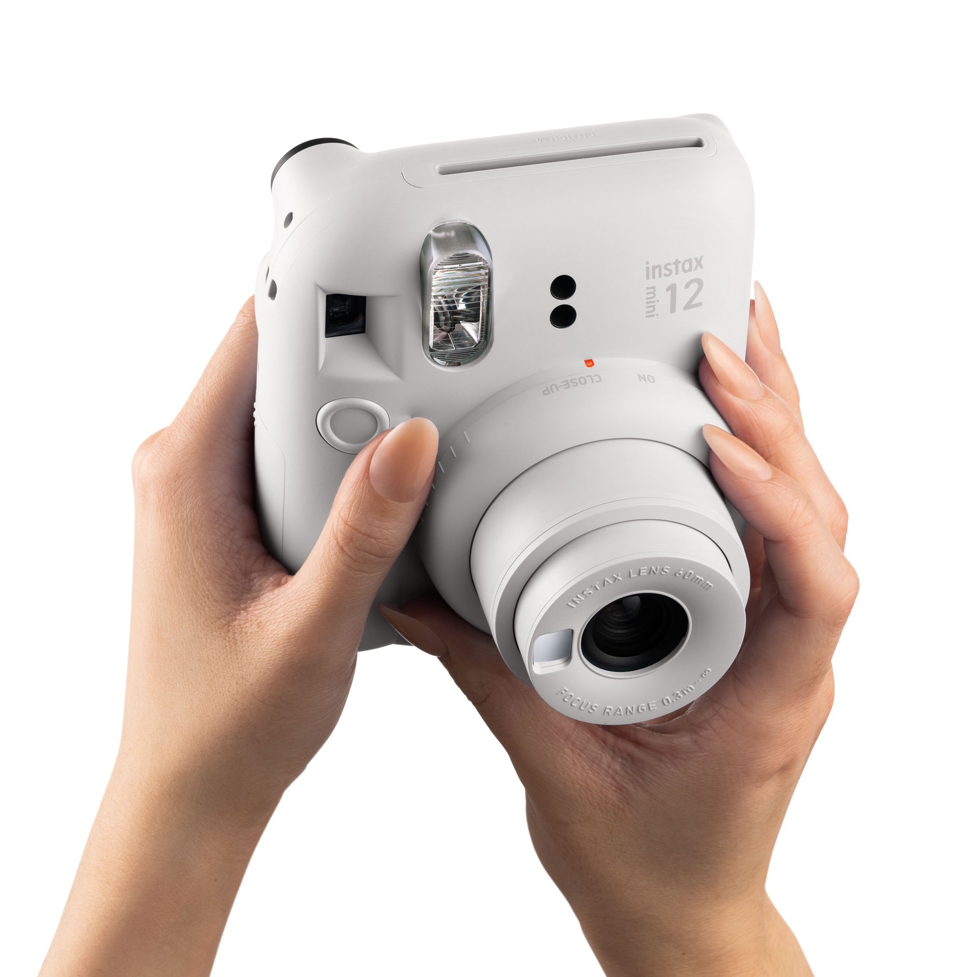 Fujifilm Instax Mini 12 kamera holdes med to hænder, klar til foto, set forfra.