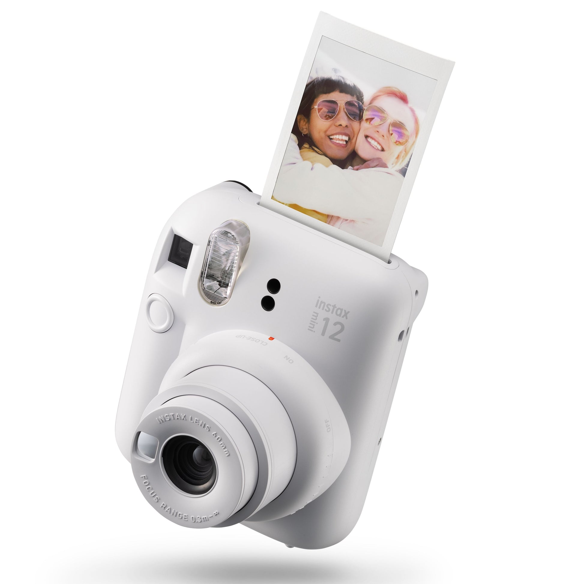 Fujifilm Instax Mini 12 kamera hvid vinklet med et printfoto af to personer der krammer kommer ud af toppen.