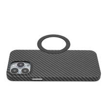 Smartphone med sort carbon cover, bagside opad, ved siden af rund sort Magnetisk adapter til trådløs opladning.