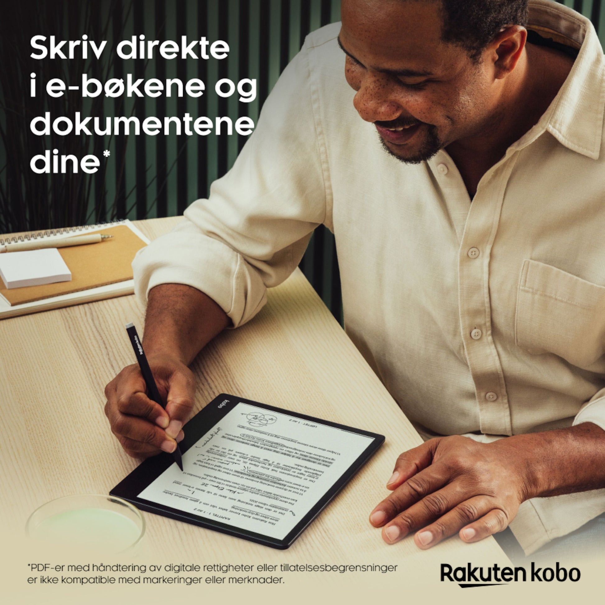Kobo Elipsa 2E e-bogslæser med Kobo Stylus 2, mand skriver på skærmen, laptop og notesbog ved siden af.