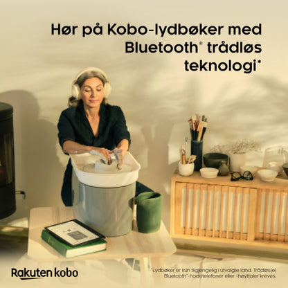 Kobo Elipsa 2E e-bogslæser med Kobo Stylus 2 bruges til lydbog via Bluetooth, synlig ved vaskemaskine og bøger.