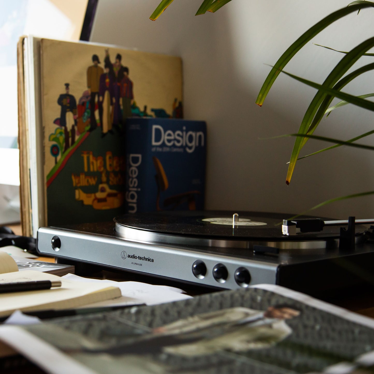 Audio Technica AT-LP60XUSB pladespiller sort i brug, "The Beatles Yellow Submarine" bog synlig i baggrund.