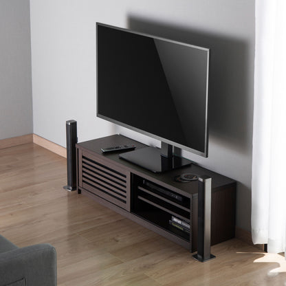 Fladskærms-TV på bordstativ til TV 37-70", højtalere på siderne, fjernbetjeninger og elektronik på mørke hylder.