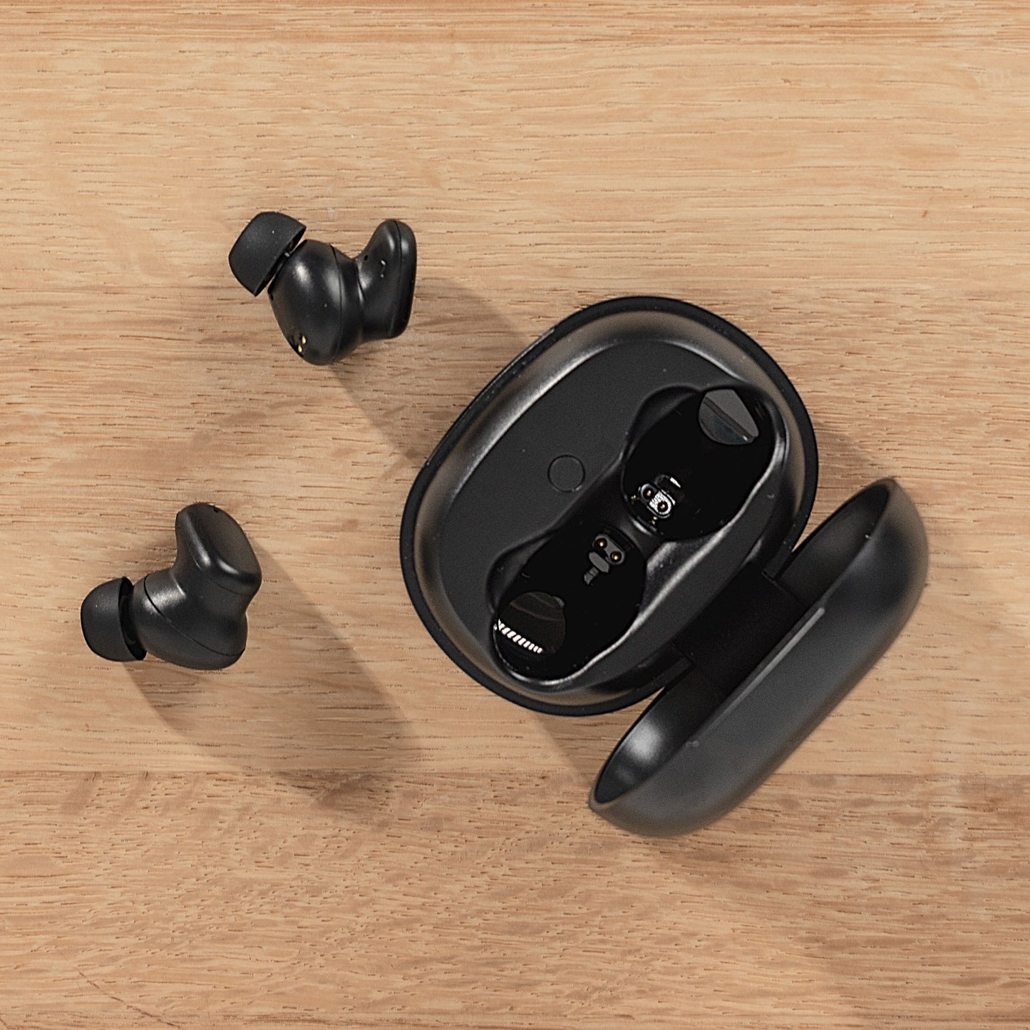 Nomadelic Solo 300 true wireless støjreducerende øretelefoner sort, åben etui med én øretelefon, to ved siden af.