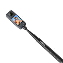 Sort Insta360 kamera monteret på Invisible Selfie Stick, skærm viser mand og kvinde tager selfie, tilbehør synlige.