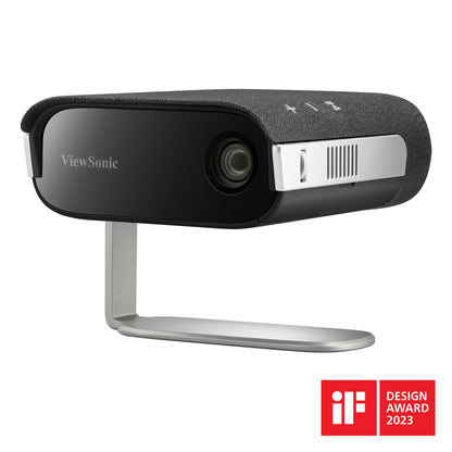 ViewSonic M1XG bærbar projektor med Harman Kardon-højttalere, stoftekstureret top, sølv 360° stativ, iF Design Award 2023 badge.