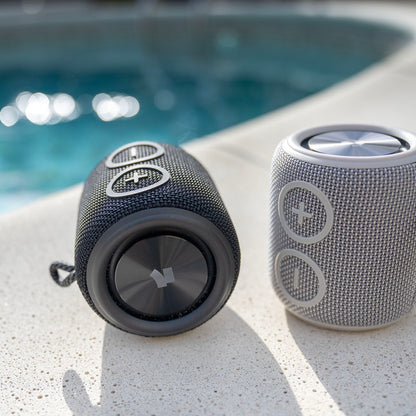 Nomadelic Loud 705 vandtæt Bluetooth-højttaler sort og grå IPX7 Bluetooth 5.0 ved poolkant.