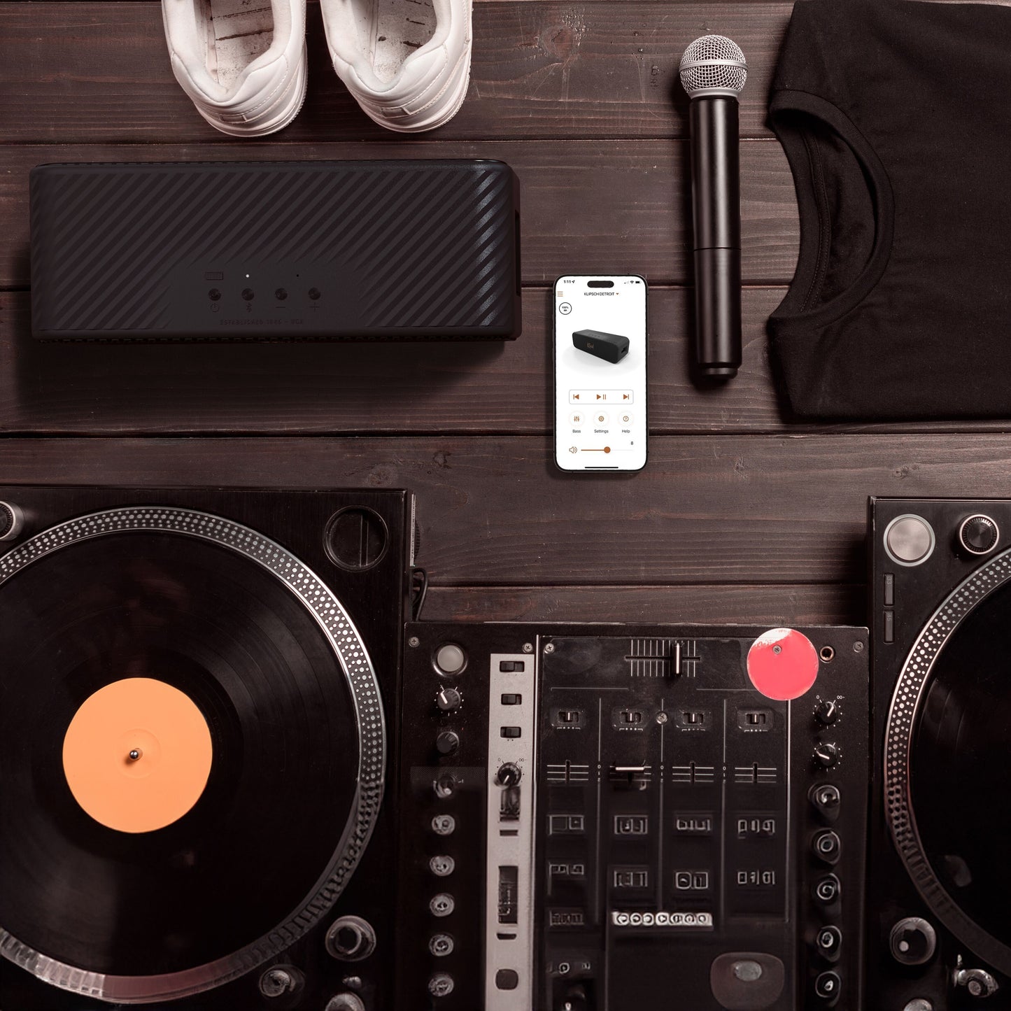 Klipsch Detroit Bluetooth-højttaler vandafvisende sort, 20+ timers batteritid, vises ved DJ-opsætning med smartphone.