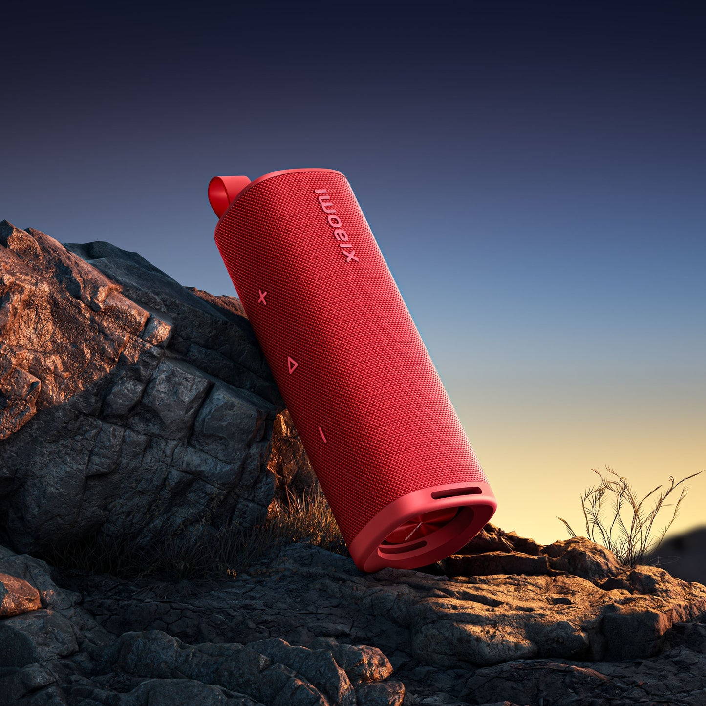 Xiaomi Lydudendørs Bluetooth-højttaler 30W rød på stenet underlag med tørt græs og klar himmel i baggrunden.