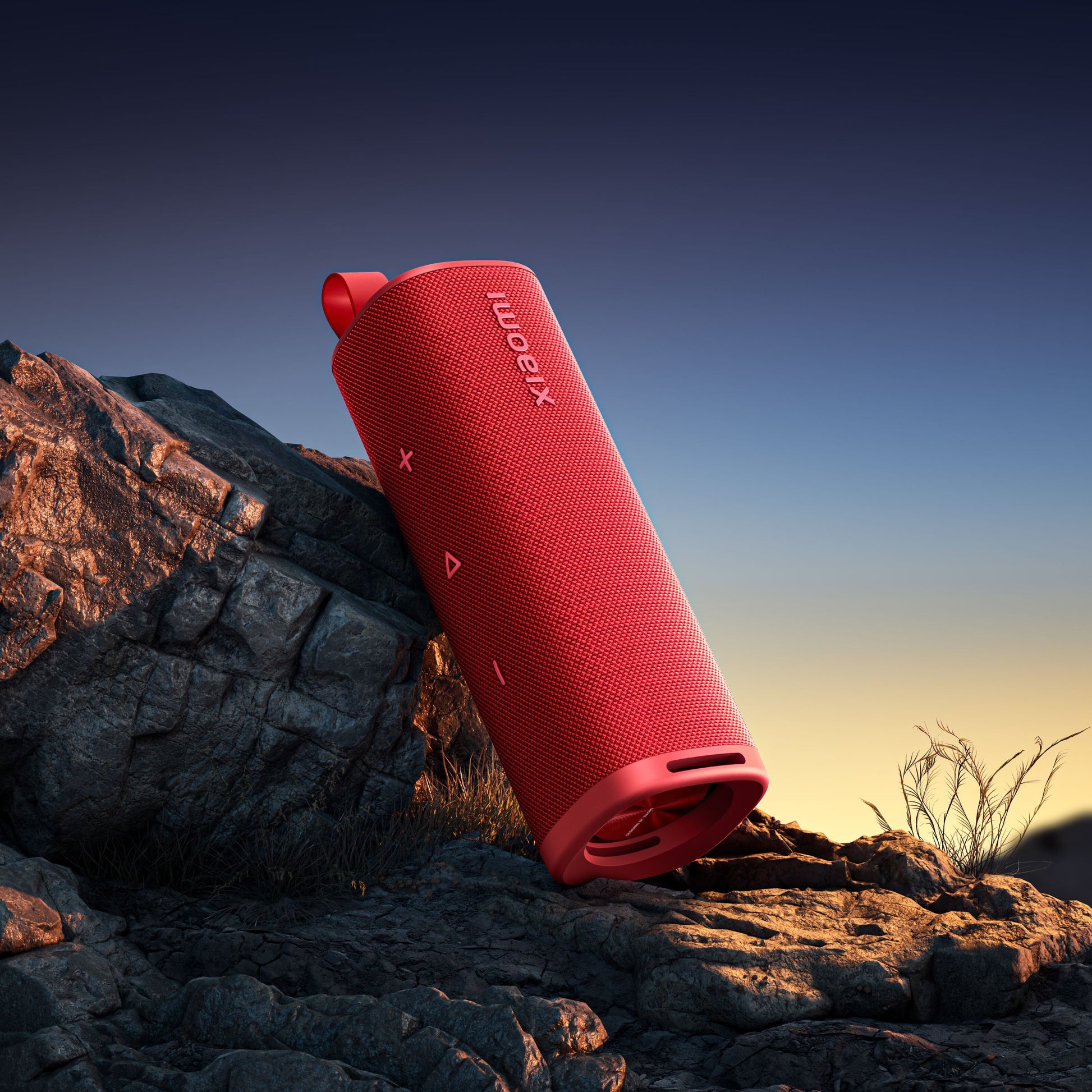 Xiaomi Lydudendørs Bluetooth-højttaler 30W rød på stenet underlag med tørt græs og klar himmel i baggrunden.