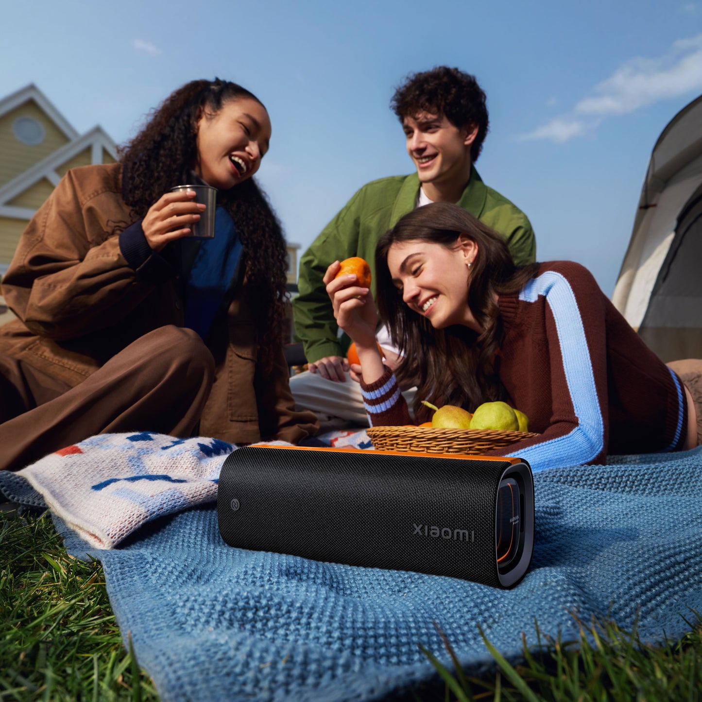 Xiaomi Sound Party bærbar Bluetooth-højttaler 50 W sort udendørs med venner, huse og telt synlige i baggrunden.