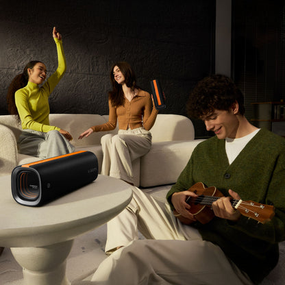 Xiaomi Sound Party bærbar Bluetooth-højttaler 50 W Sort IP67 holder af kvinde, sofa og personer i baggrunden.