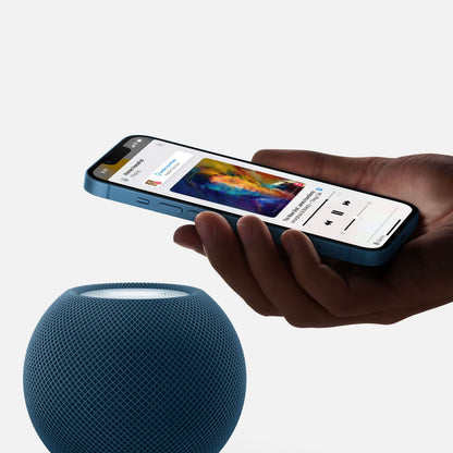 IPhone med musikstyring tæt på hvid Apple HomePod mini med Siri stemmestyring og audio handoff.