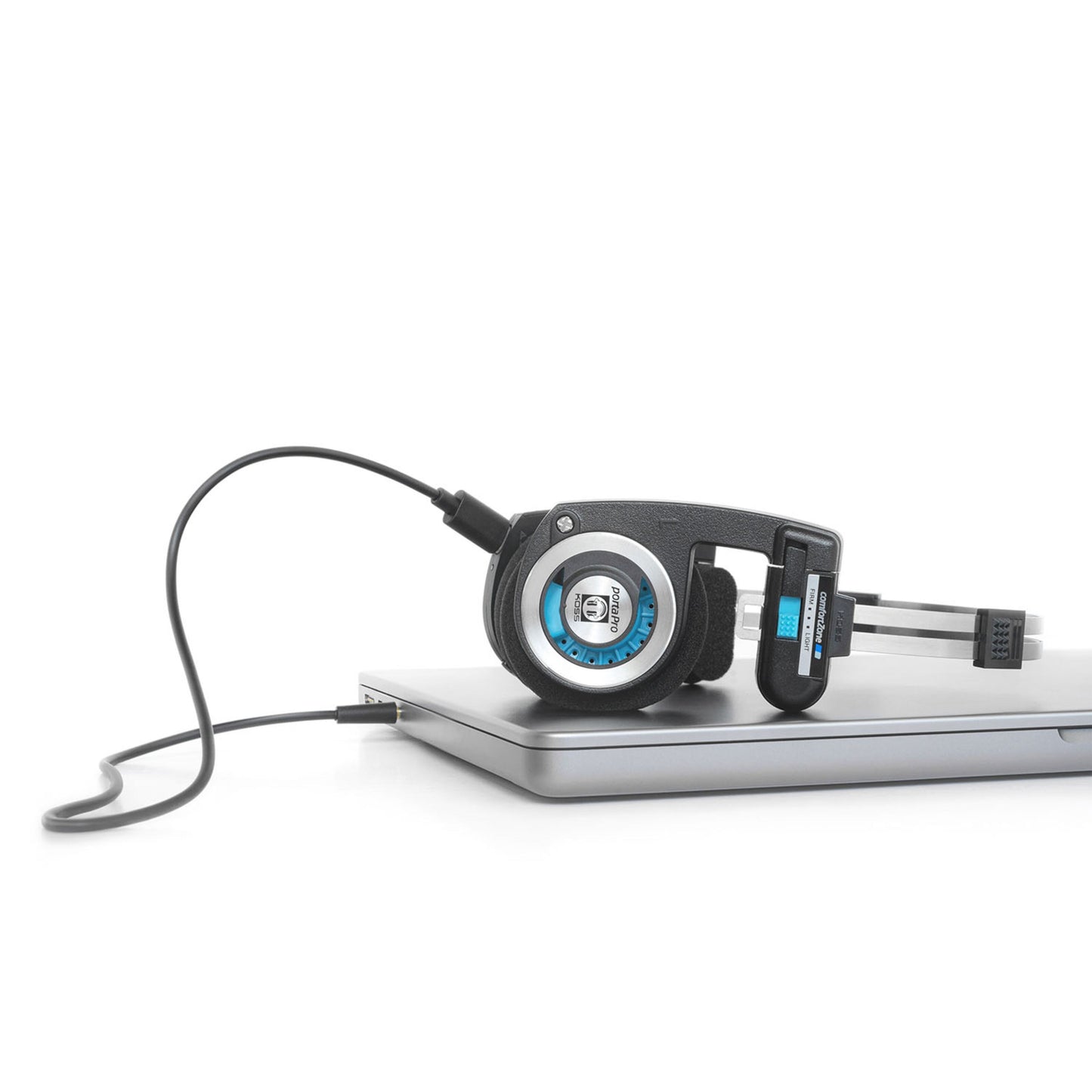 Koss Porta Pro Trådløs 2.0 on-ear hovedtelefoner foldbare, sort kabel tilsluttet lukket sølvfarvet laptop.