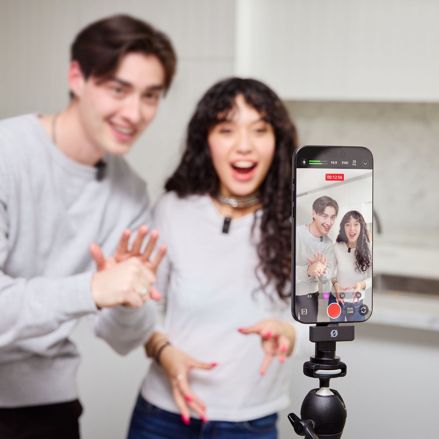 Røde Wireless GO mikrofon i sort påmonteret smartphone på stativ under videooptagelse i køkkenmiljø.
