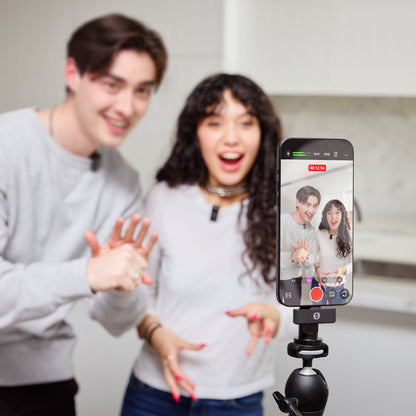 Røde Wireless GO mikrofon i sort påmonteret smartphone på stativ under videooptagelse i køkkenmiljø.