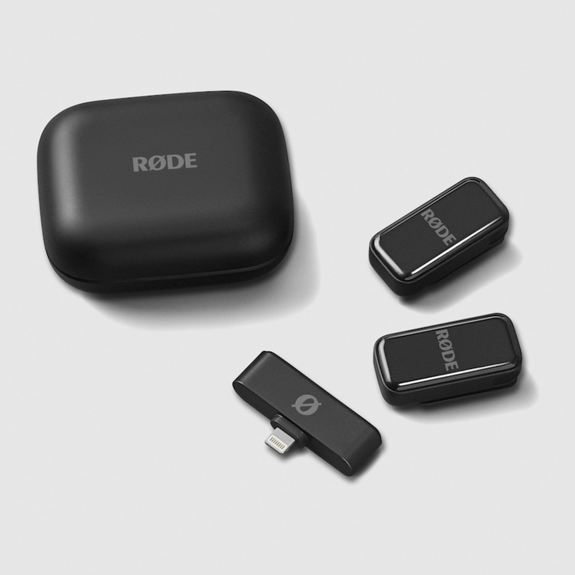 Røde trådløse mikrofoner med afrundet opladningsetui, to transmittere og Lightning-modtager.