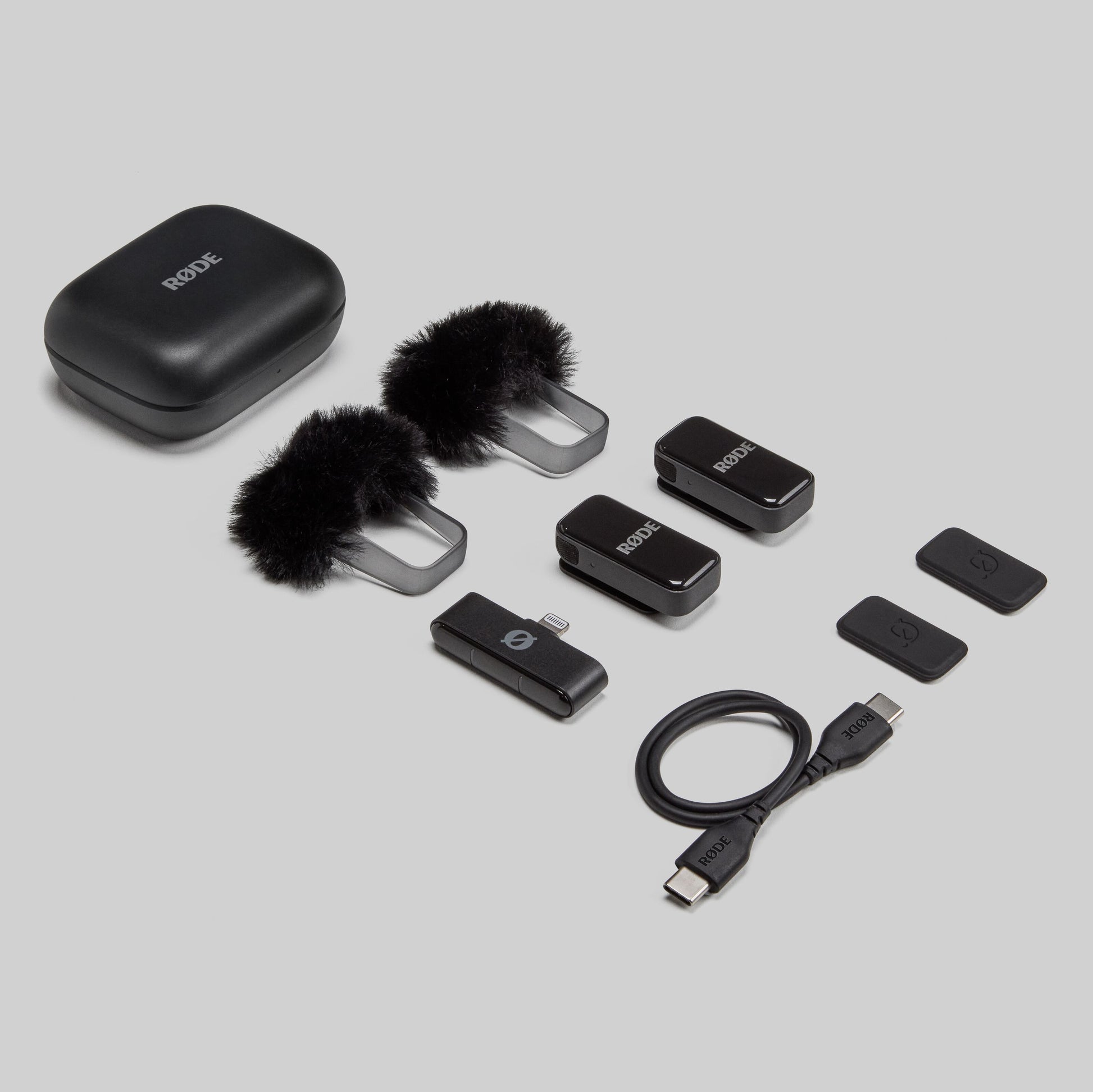 Røde trådløst mikrofonsæt med opladeetui, 2 furry vindskærme, 2 transmittere, modtager, klip og kabler.