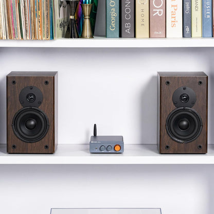 Fosi Audio forstærker Bluetooth 2x100W, stor orange knap, sammen med træsatelithøjttalere på hylde.