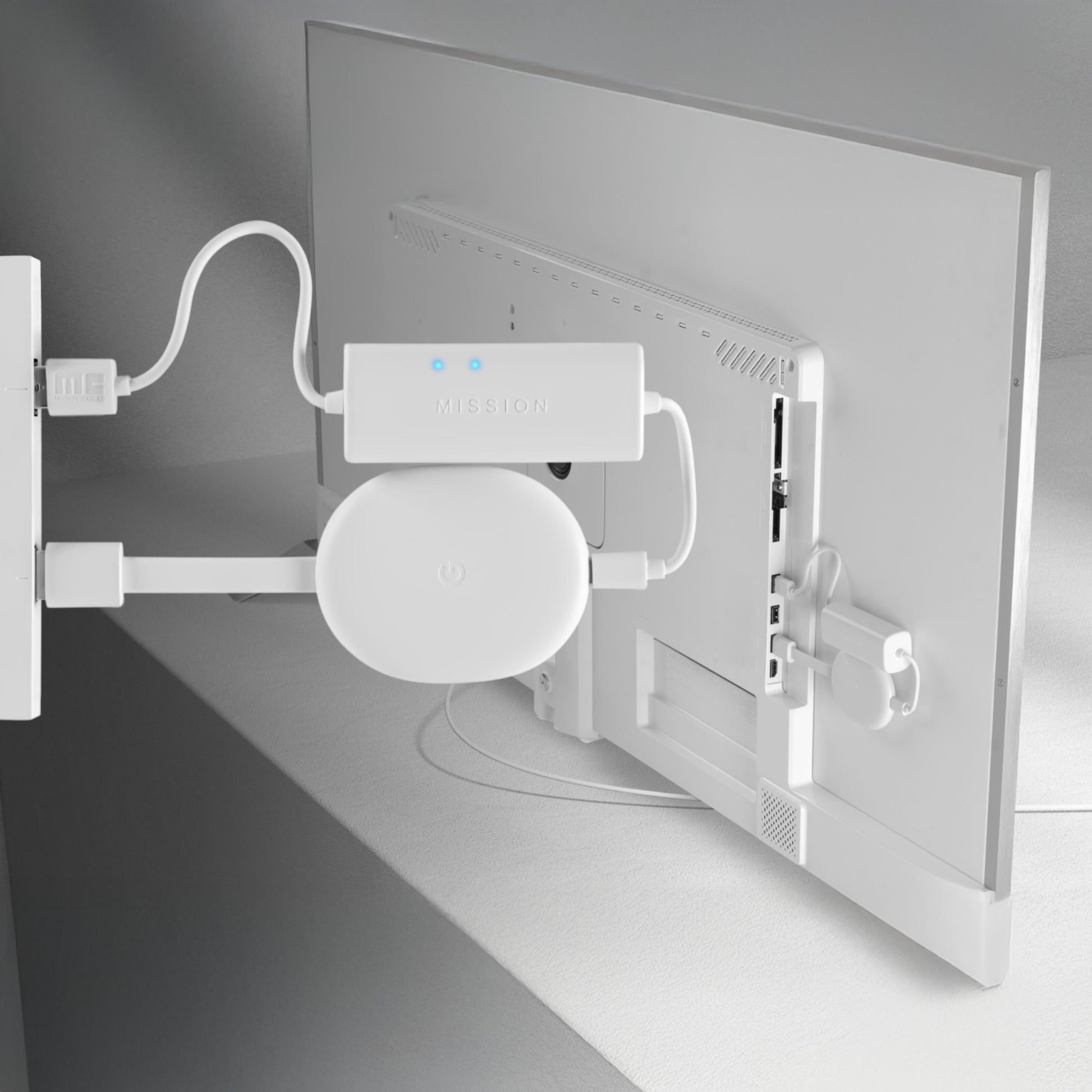 TV-bagpanel med hvid strømadapter, Mission power hub med blå LED og Google Chromecast med Google TV monteret bag skærmen.