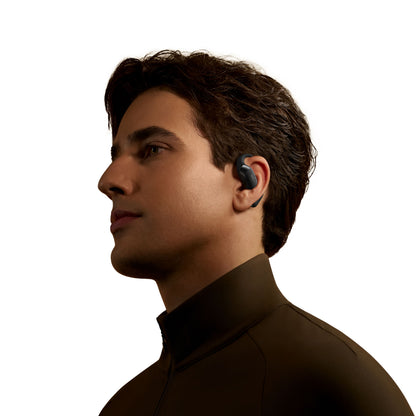 Shokz OpenFit 2+ TWS øretelefoner Sort med åben design ses i profil i øret på mørkhåret mand iført brun jakke.