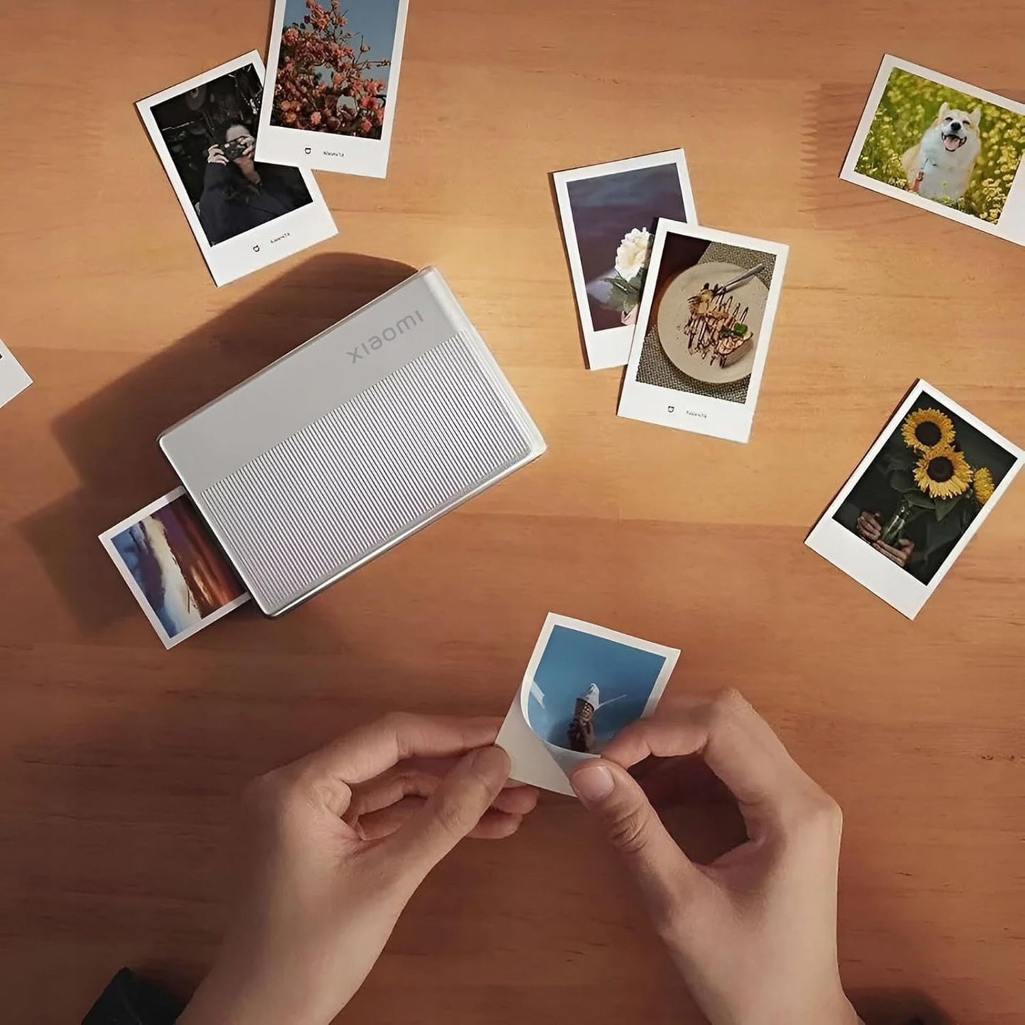 Xiaomi Bærbar fotoprinter 1S ZINK Zero Ink, printer på træbord med udskrift og fotos af blomster, mad og hund.