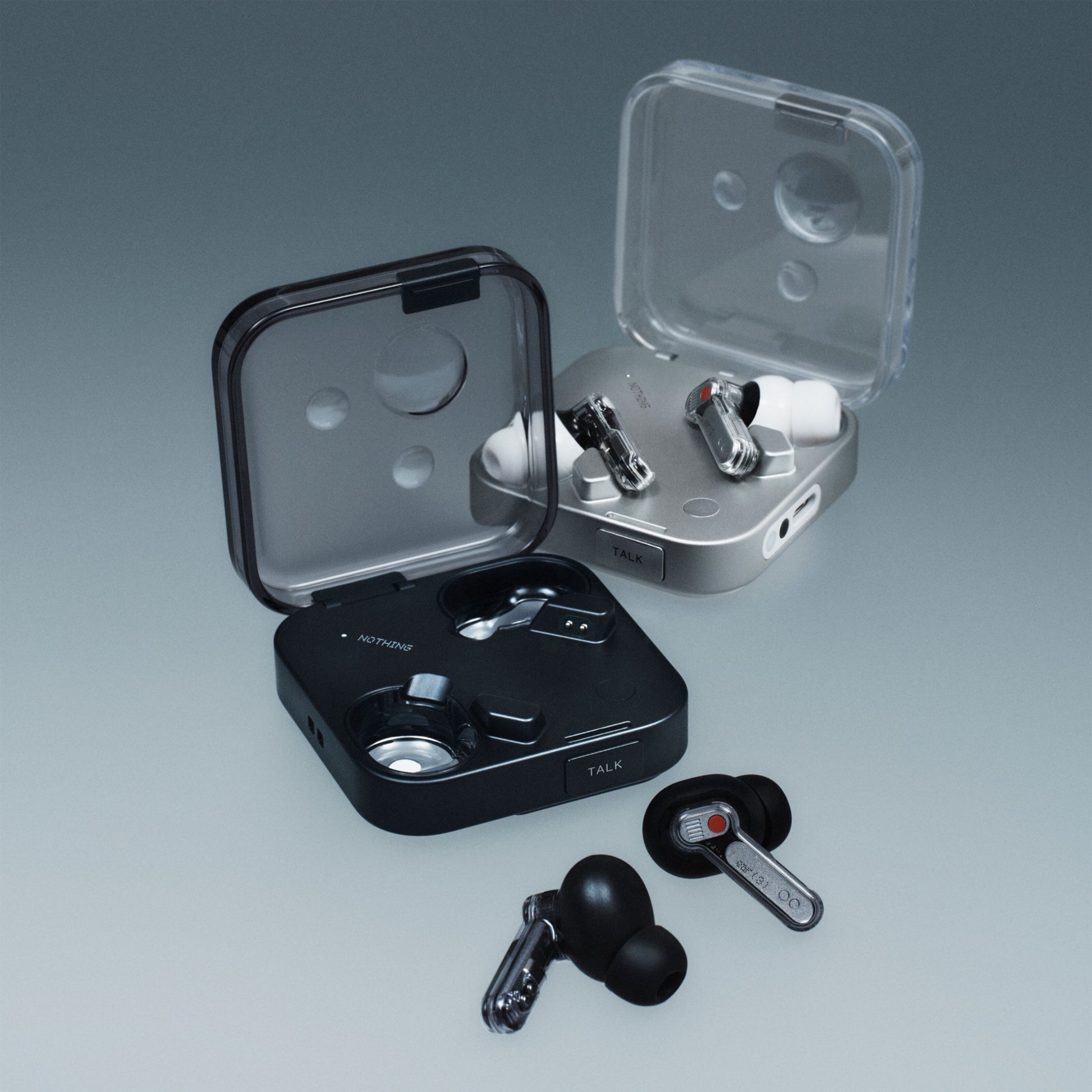 Nothing Ear (3) høretelefoner sort og hvid, hver med kvadratisk etui med transparent låg, én earbud ved siden af etuiet.
