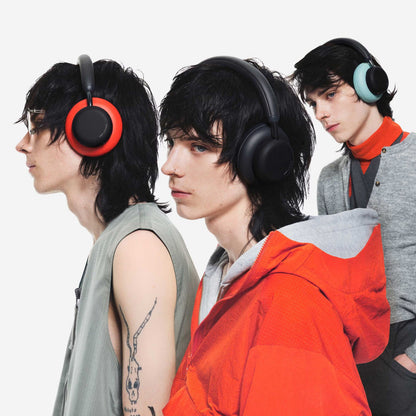 Nothing CMF Headphone Pro Hybrid ANC-hovedtelefoner i mørkegrå, rød og mintgrøn bæres af unge med mørkt, pjusket hår.
