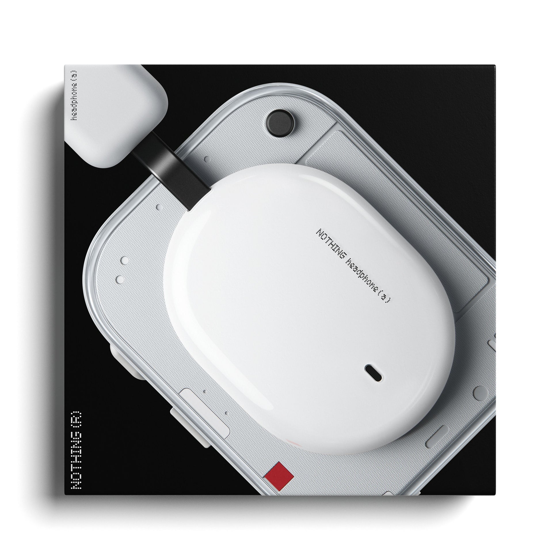 Nothing Headphone (a) hvid trådløs over-ear høretelefoner etui på afrundet hvid enhed med tilsluttet oplader.