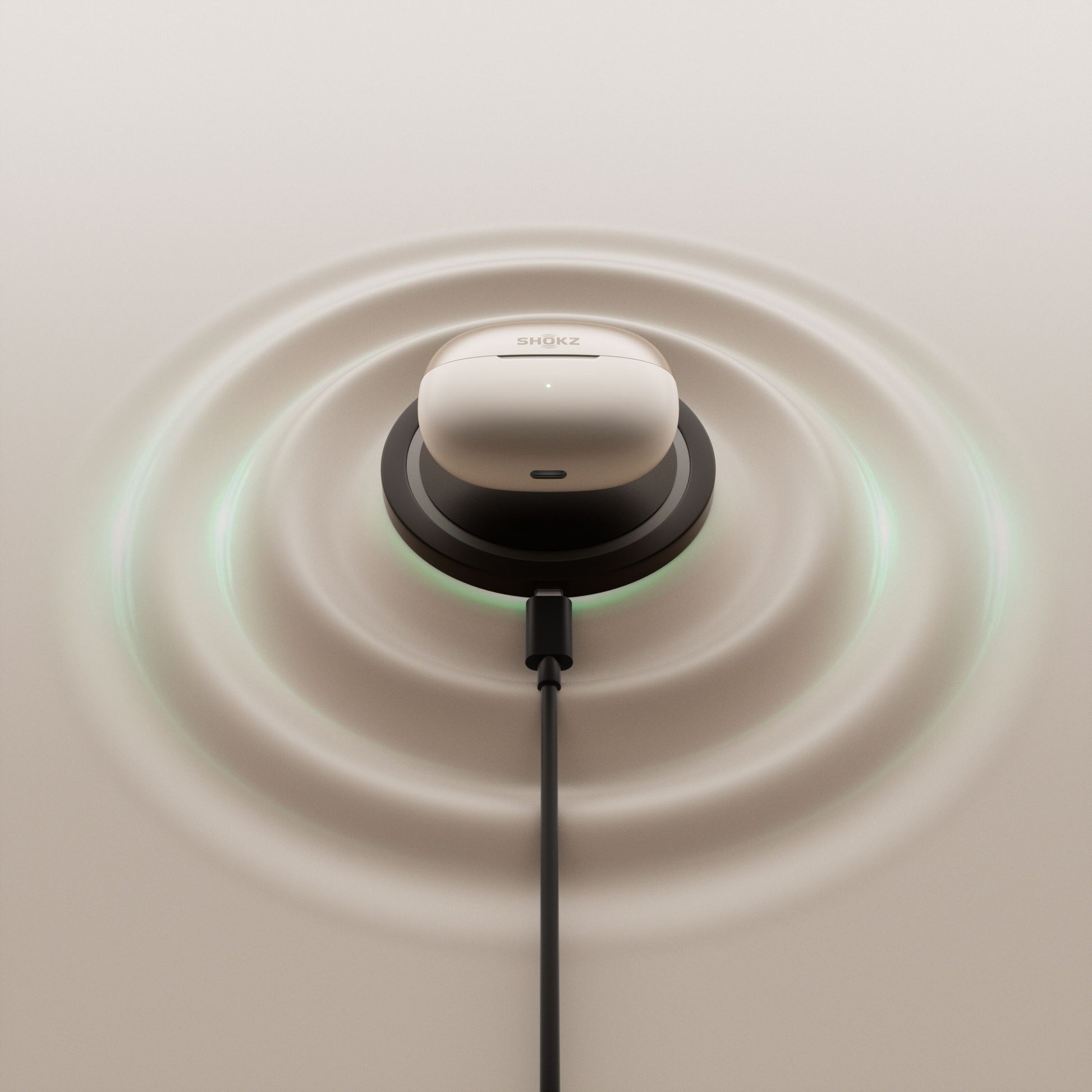 Shokz OpenDots One grå trådløse åbne clip-on-hovedtelefoner i opladningsetui på sort pad med USB-C og lyseffekt.