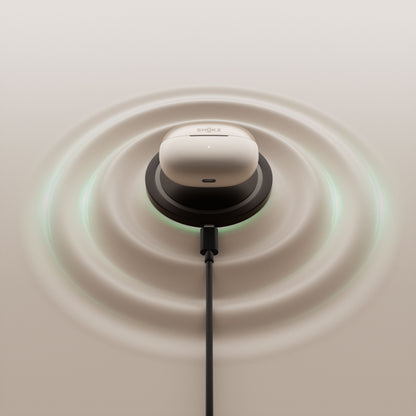 Shokz OpenDots One grå trådløse åbne clip-on-hovedtelefoner i opladningsetui på sort pad med USB-C og lyseffekt.
