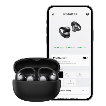 Shokz OpenDots One trådløse åbne clip-on høretelefoner sort i etui, med smartphone der viser appens batteristatus.