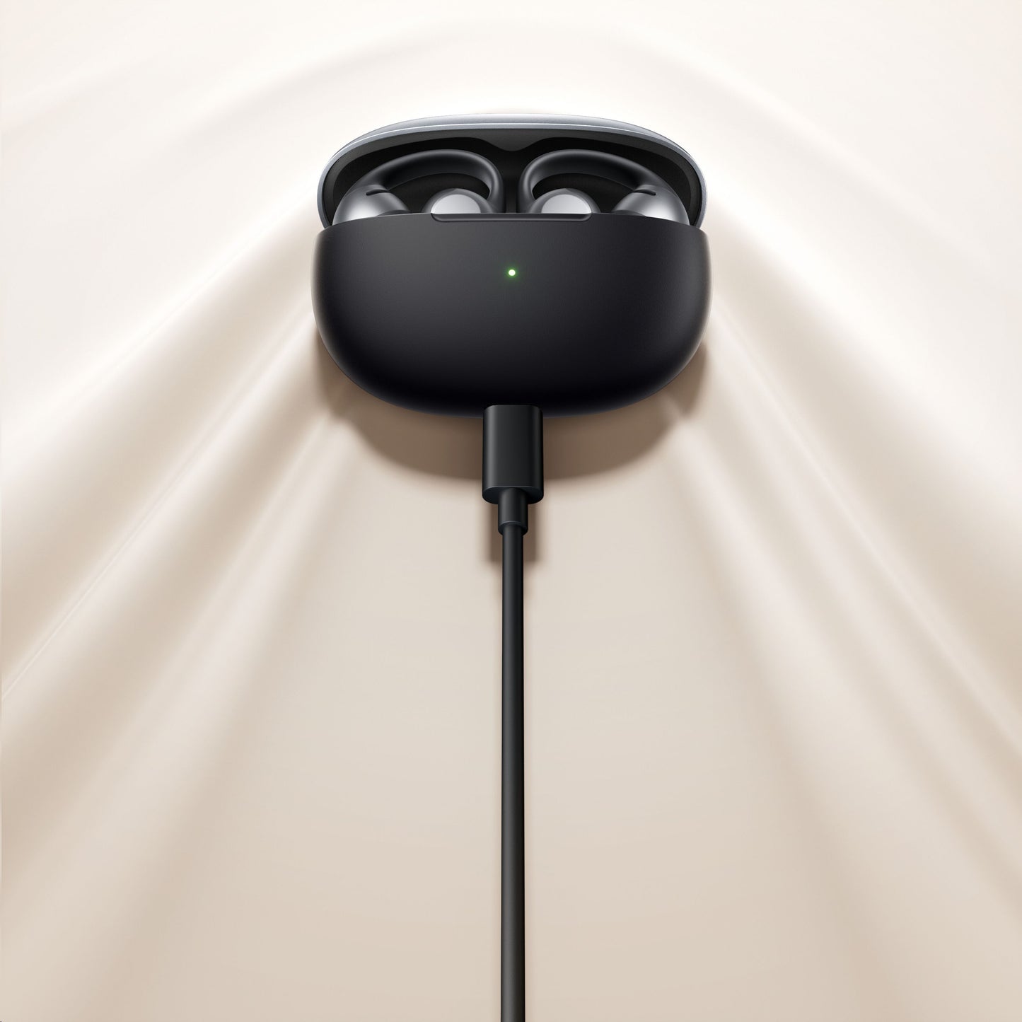 Shokz OpenDots One trådløse åbne clip-on høretelefoner i åbent opladningsetui med grøn LED, cremefarvet underlag.