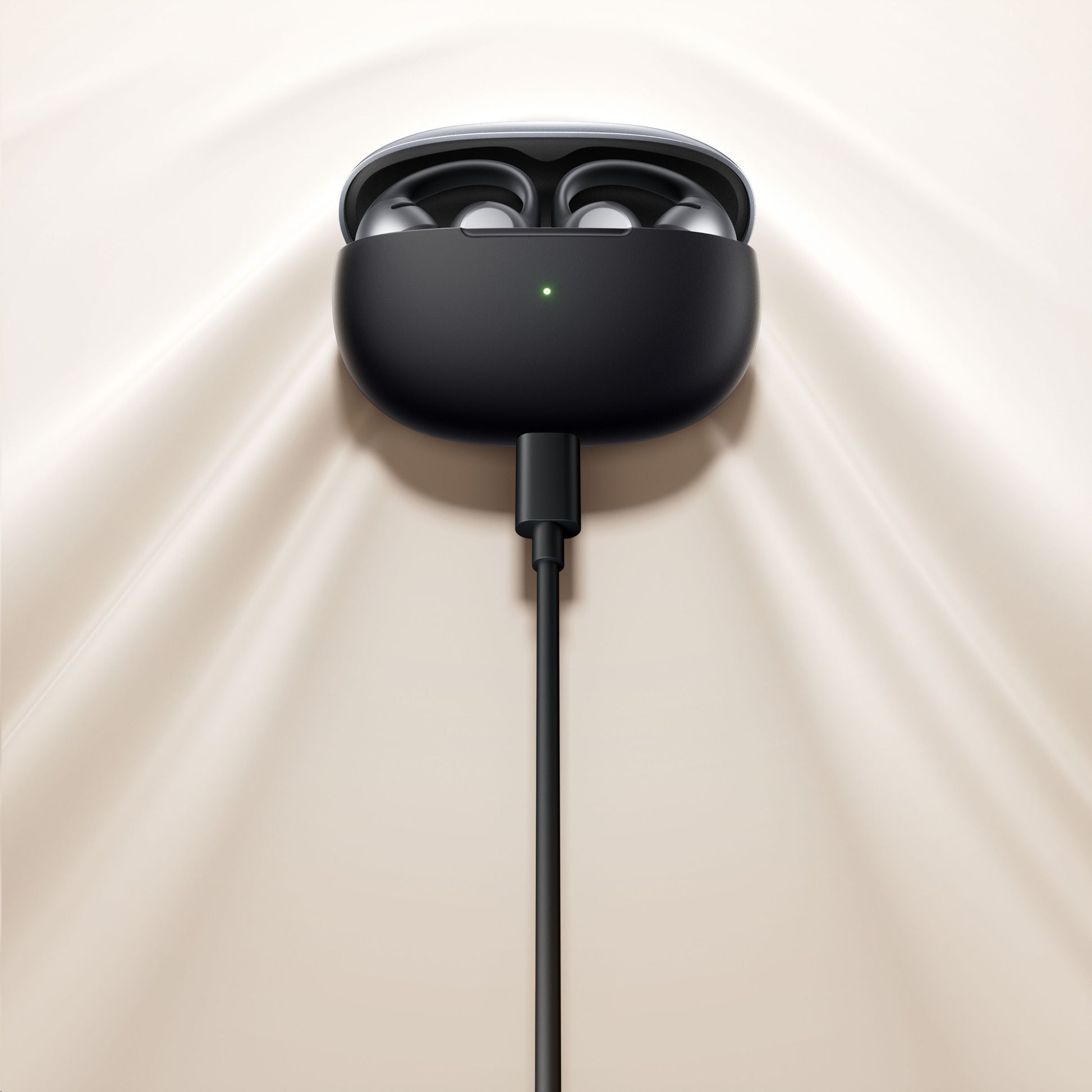 Shokz OpenDots One trådløse åbne clip-on høretelefoner i åbent opladningsetui med grøn LED, cremefarvet underlag.