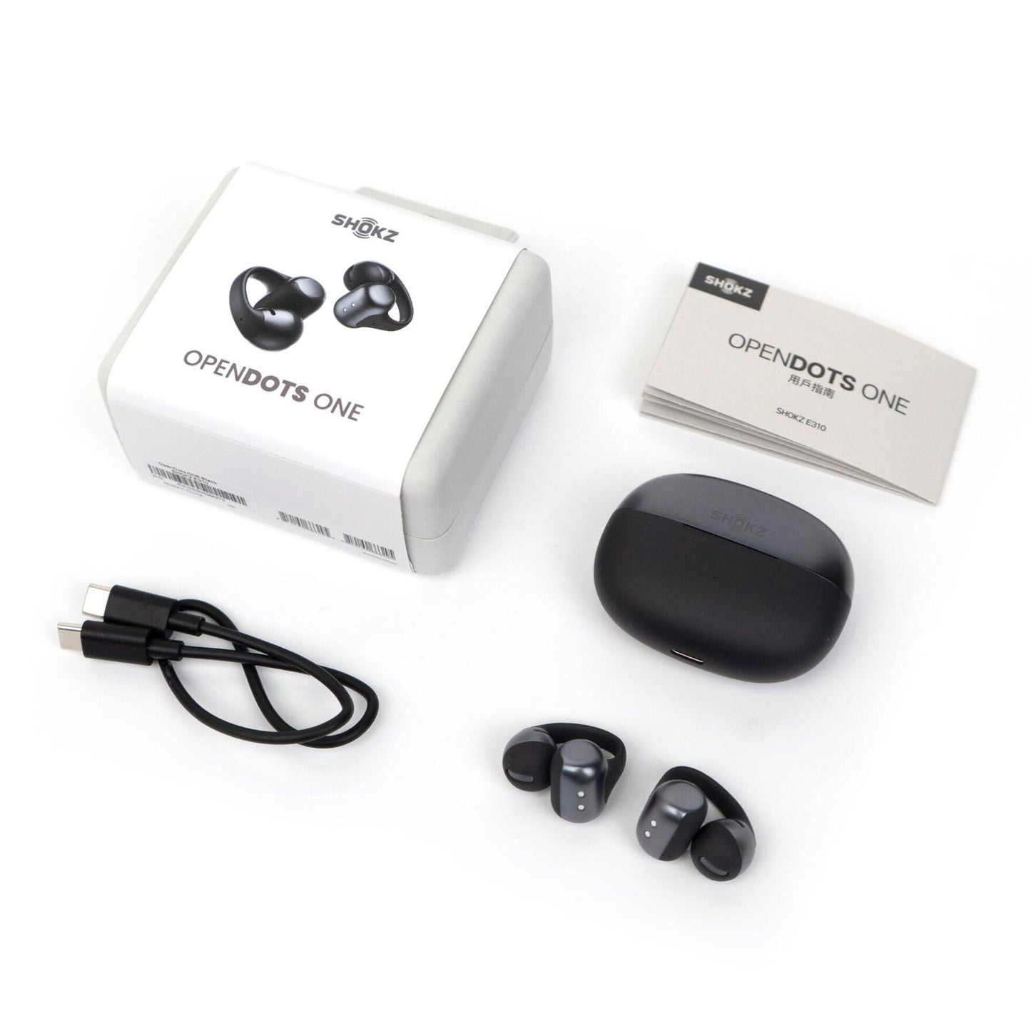 Shokz OpenDots One trådløse åbne clip-on høretelefoner sorteret med opladningsetui, USB-C kabel, brugervejledning og produktæske.