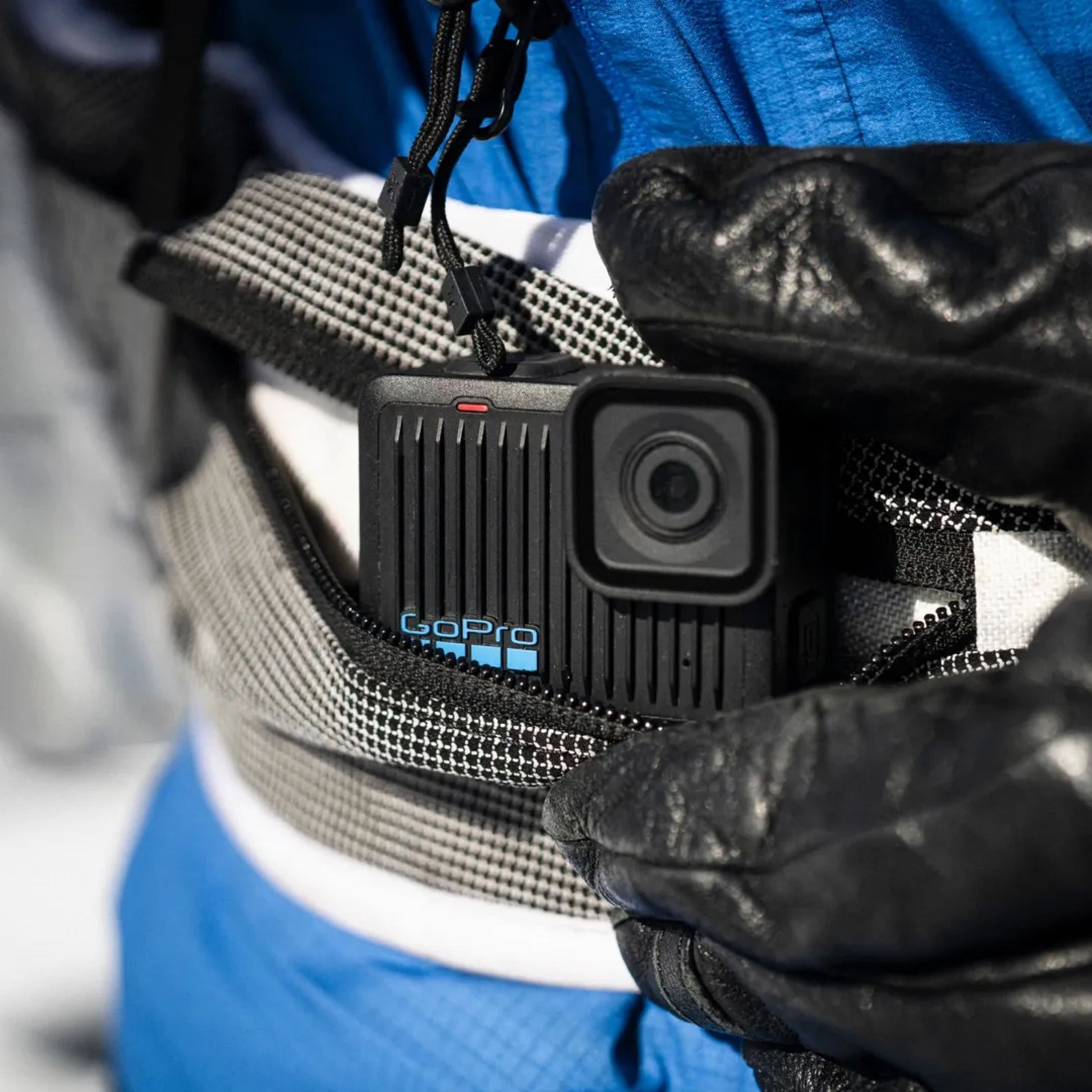Gopro HERO actionkamera 4K på grå rem holdes af person i blå jakke og sorte handsker.