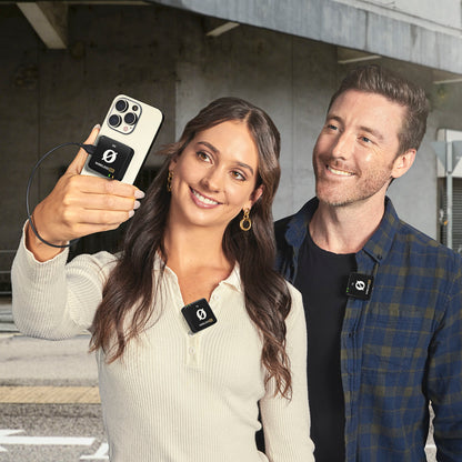 Røde Trådløs ME Dual sort mikrofon på skjorte, koblet til smartphone til videooptagelse, synlig udendørs kontekst.