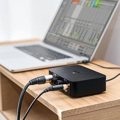 Sort Røde AI1 audio interface med kabler ved siden af åben laptop med musiksoftware, del af NT1 + AI1 Studio Bundle.