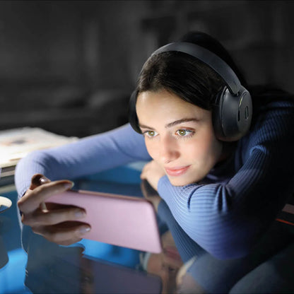 MIXX StreamQ Surround TV Trådløse hovedtelefoner på kvinde med langt mørkt hår, blå sweater, pink smartphone.