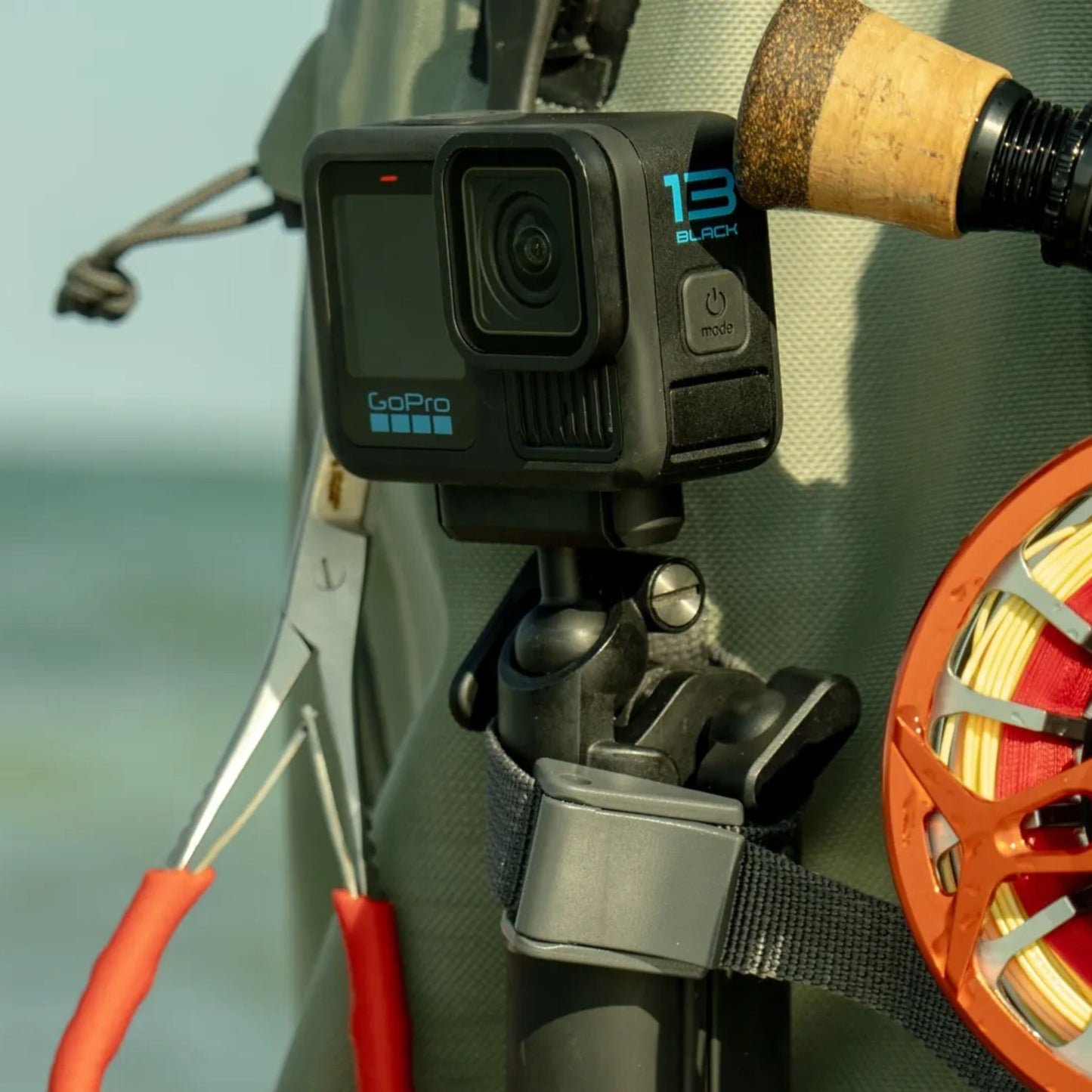 GoPro magnetisk lås kugleled monteret på fiskevest rem med synlig fluefiskestang, hjul og tang.