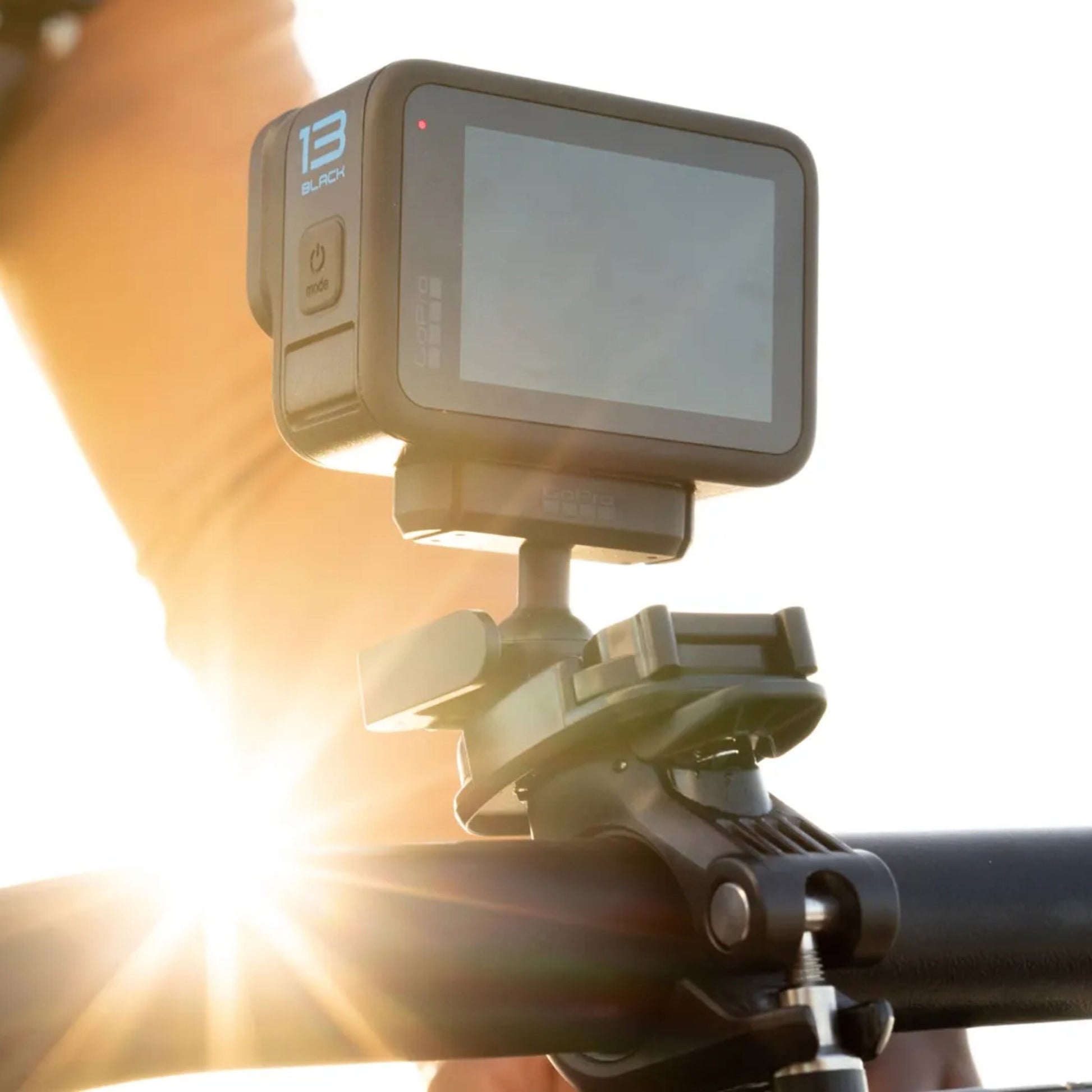 Gopro Magnetisk lås kugleled monteret på cykelstyr, sollys i baggrunden, sløret arm tæt ved.