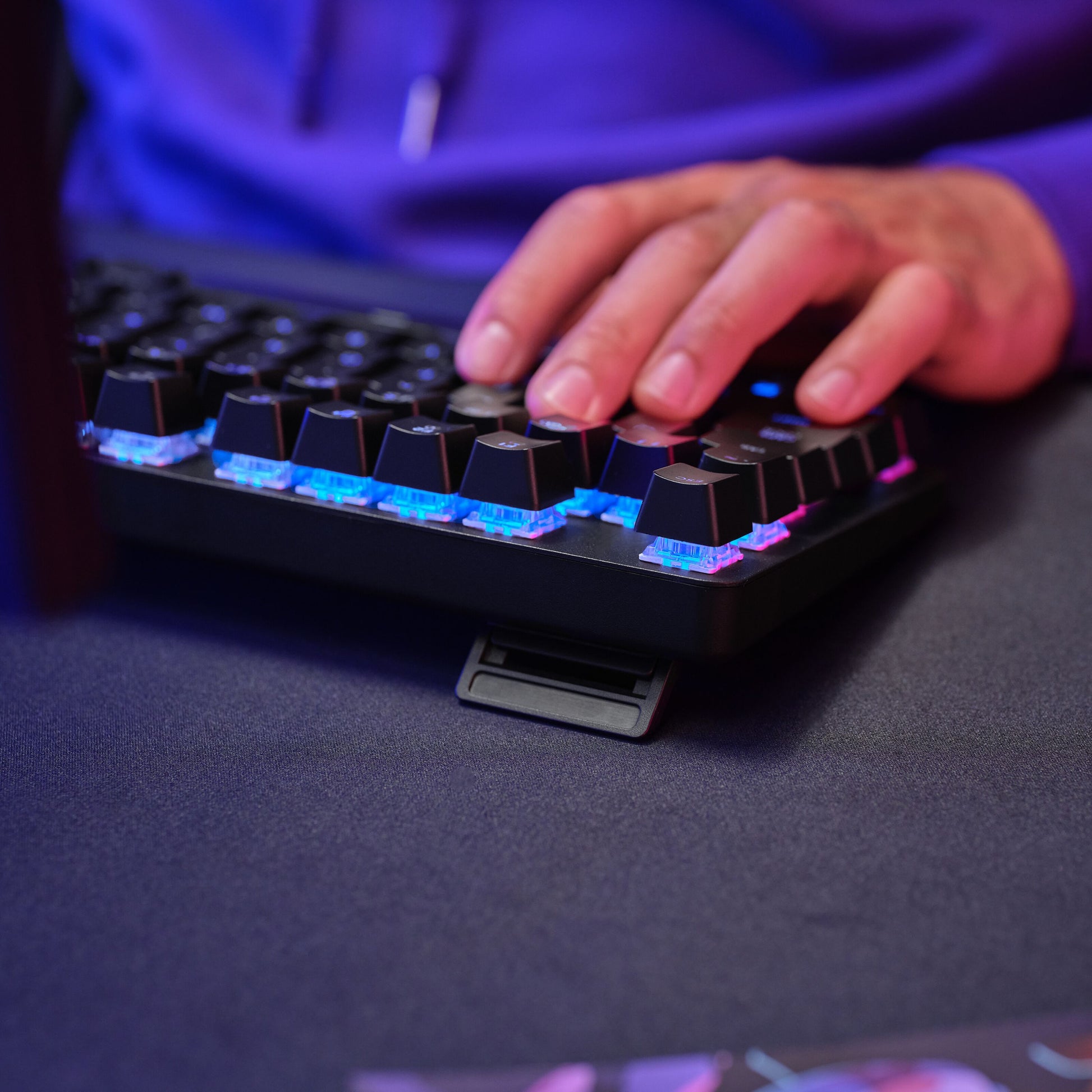 Trust GXT 871 Zora Mekanisk Gamingtastatur med RGB-belysning og oplyst taster brugt ved mørkt skrivebord.