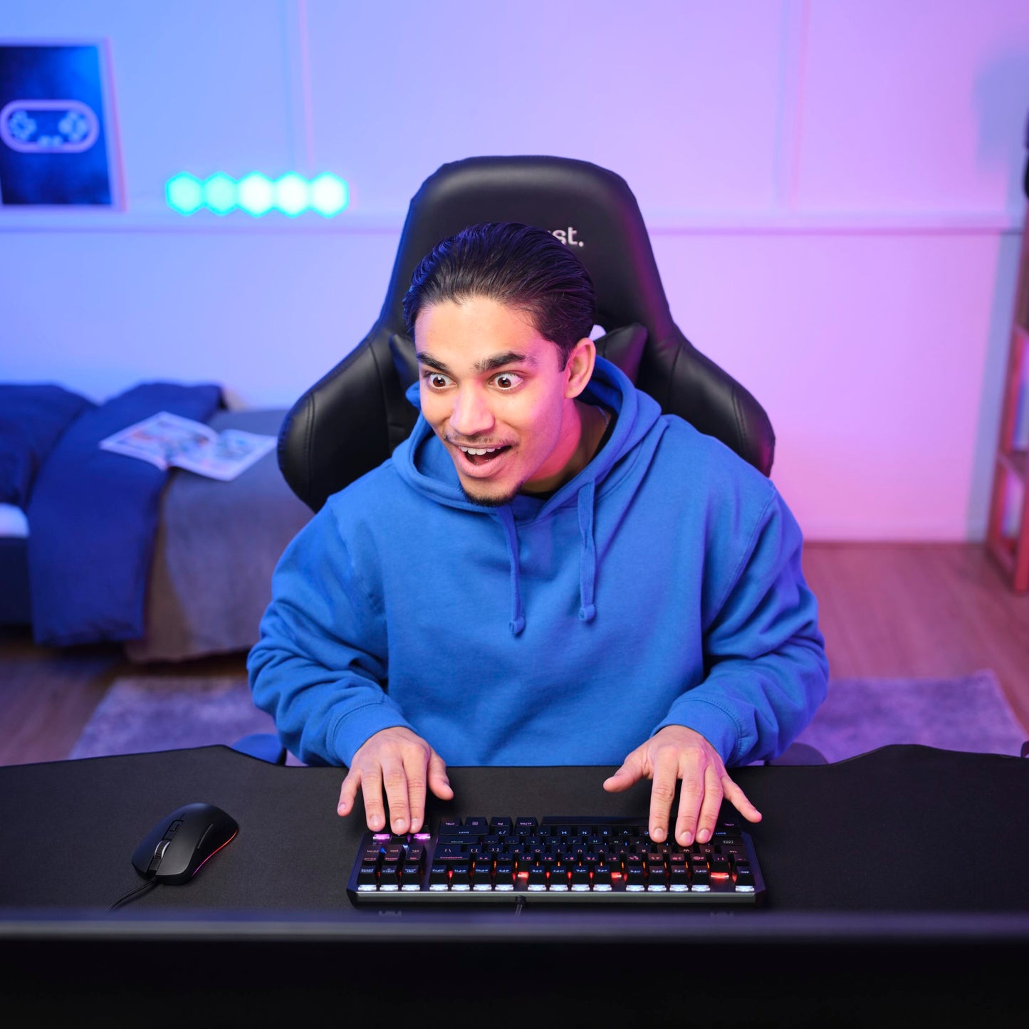 Trust GXT 924 Ybar+ Gamingmus med programmerbare knapper og PMW3389 sensor på skrivebord, blå hættetrøje.