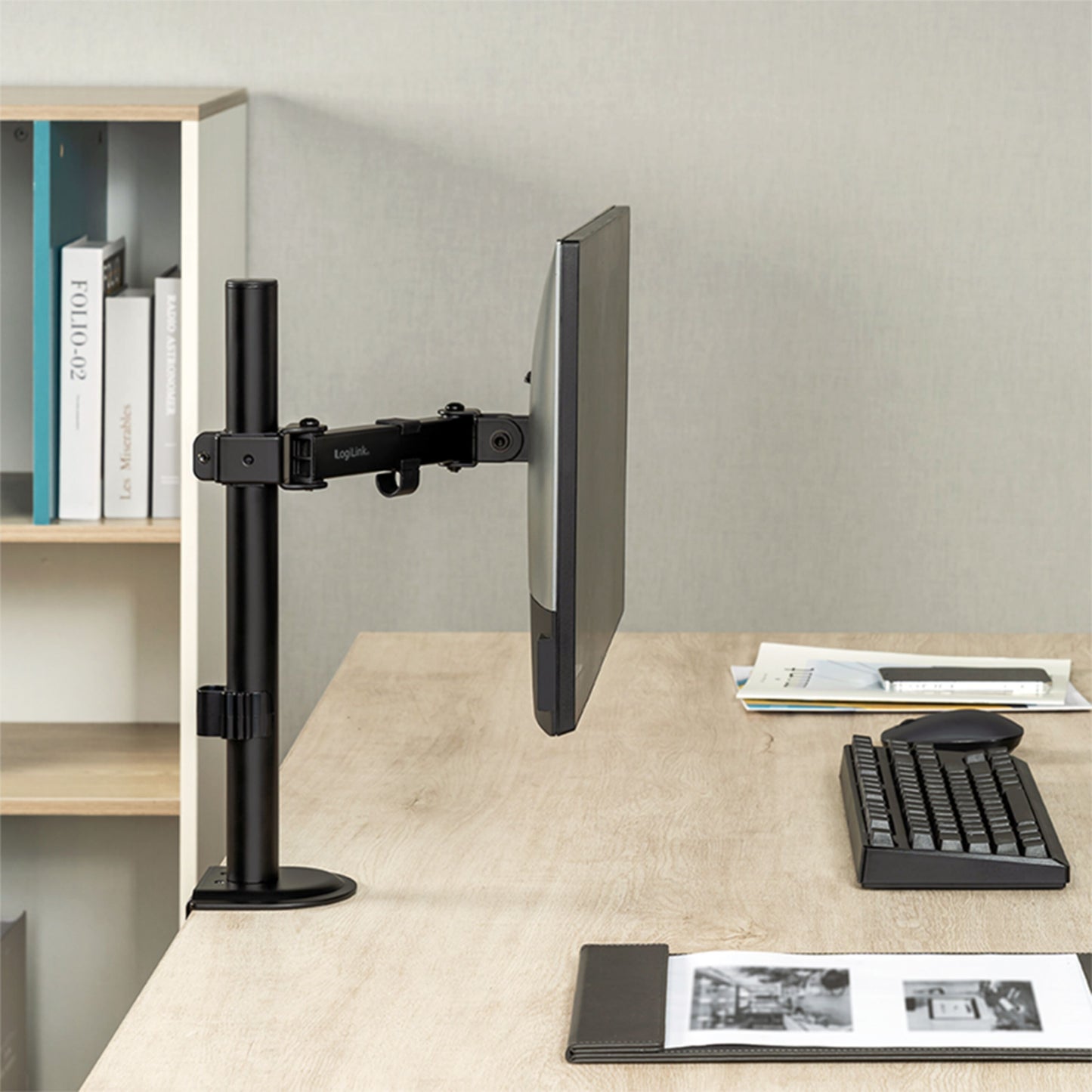 Logilink bordbeslag til 17-32" skærm monteret på træbord med tastatur og mus, hylder med bøger og ringbind bagved.