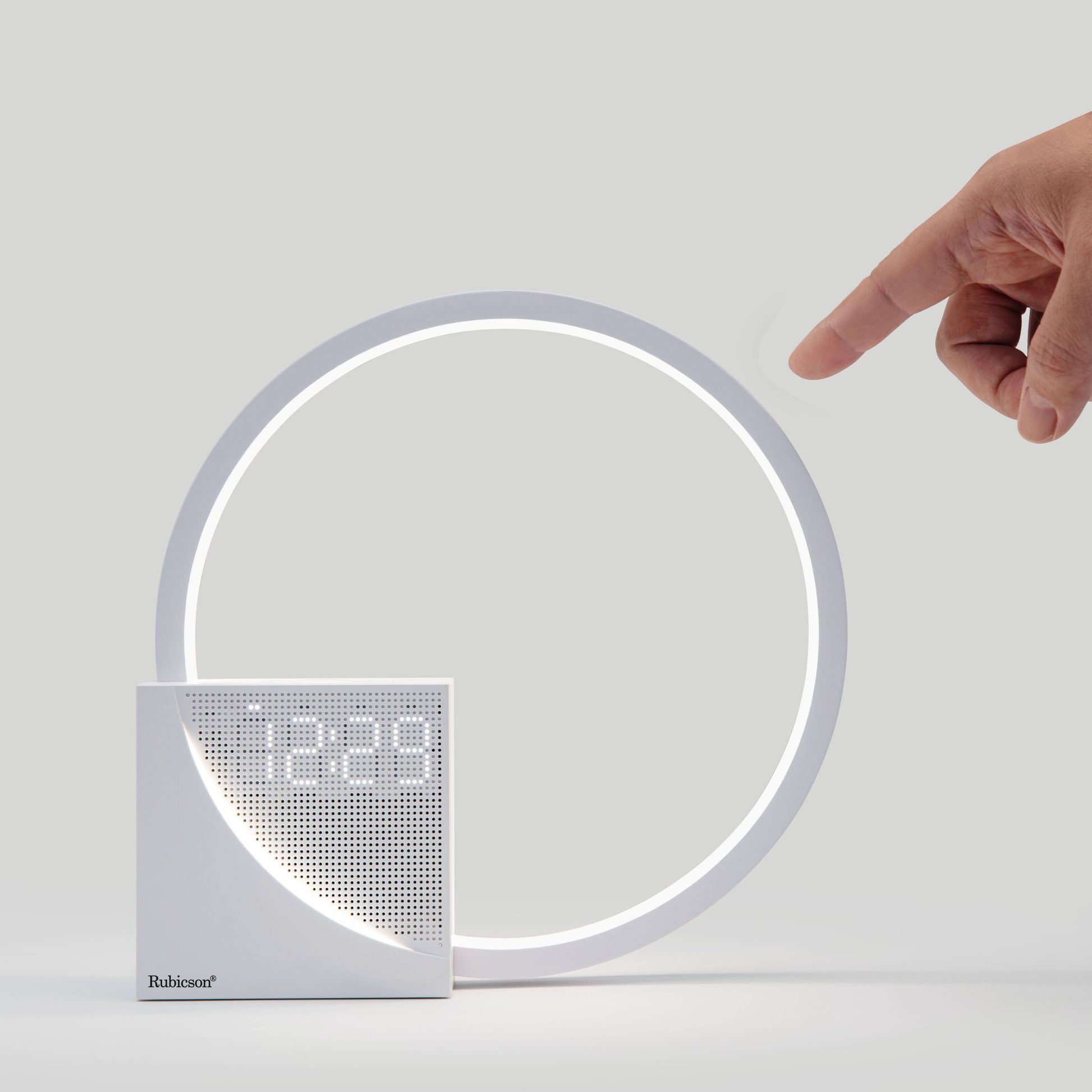 Rubicson Wake-up light vækkeur med natlampe, vises ved siden af ur der viser 12:29, hånd rækker ud efter vækkeuret.
