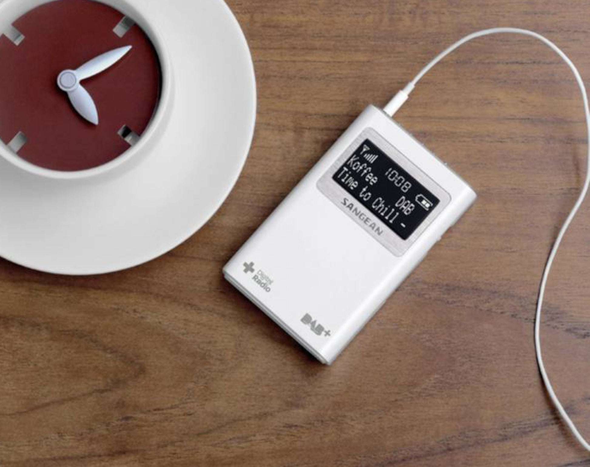 Sangean DPR-39 DAB+ radio med høretelefoner, sort, display viser "Time to Chill", placeret ved siden af kopformet ur.