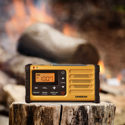 Sangean håndsvingradio FM USB-C i gul, viser 100.7, flere knapper og drejeskiver synlige på fronten.